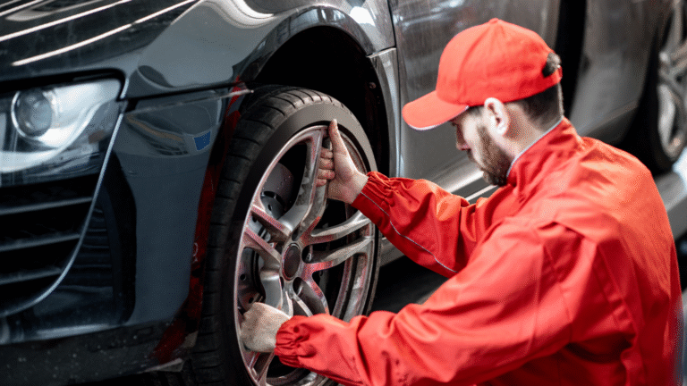 Mechanic performing car maintenance by inspecting and tightening the wheel of a modern vehicle in an auto repair shop.