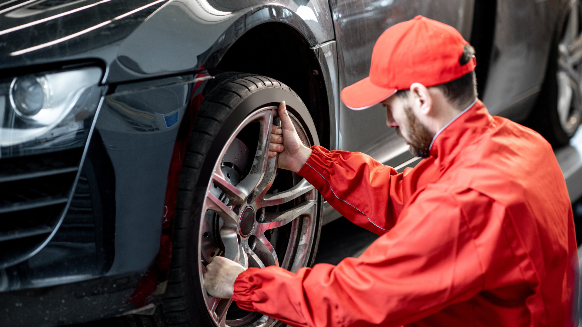 Mechanic performing car maintenance by inspecting and tightening the wheel of a modern vehicle in an auto repair shop.