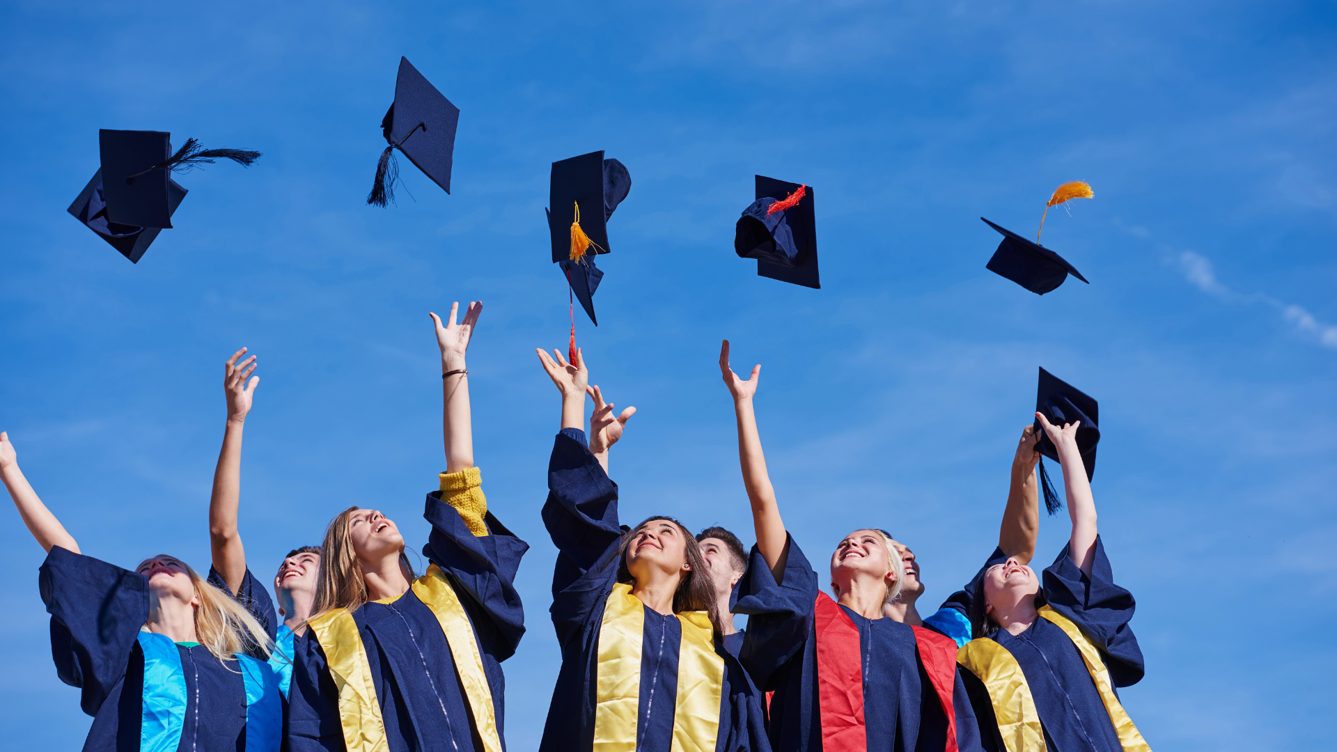Group of diverse students celebrating graduation by throwing caps in the air, symbolizing achievement and success in education.