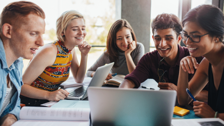 College students collaborating with laptops and books, engaging in microlearning activities through group study and digital tools.