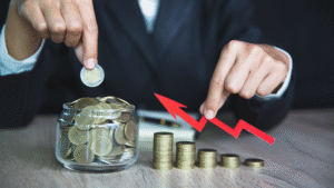 Business person stacking coins and pointing at growth arrow to symbolize how to build wealth through saving and investment.