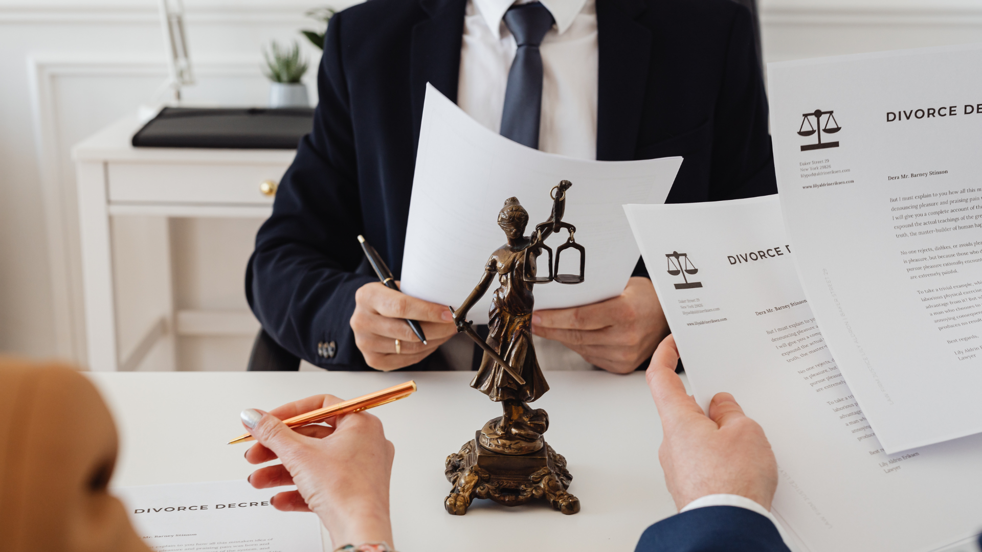 Civil lawyers discussing divorce decree documents with clients at a legal office, featuring Lady Justice statue on the desk.