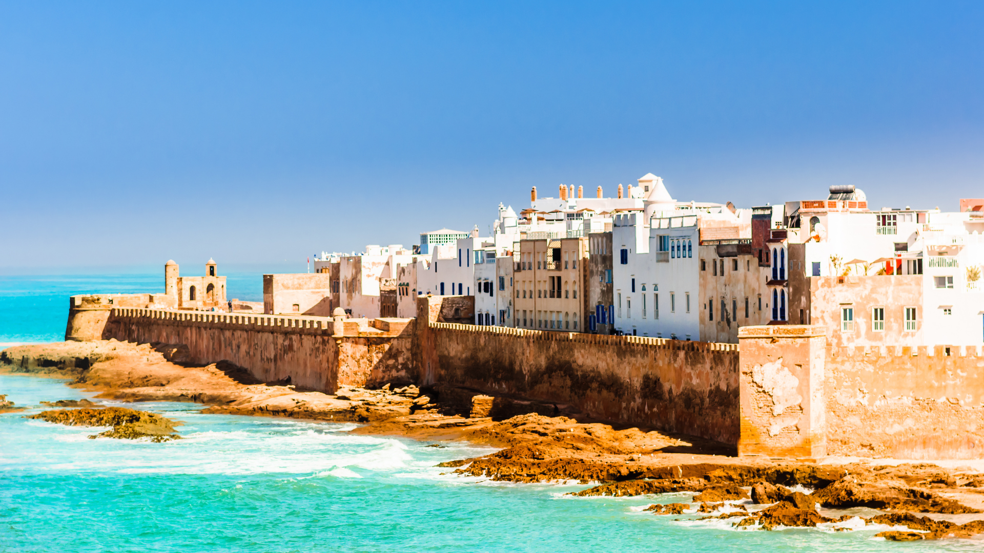 Coastal view of a historic fortified city in Morocco with whitewashed buildings and turquoise waters, representing scenic African destinations.
