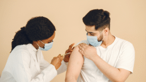 Doctor giving a vaccine injection to a man wearing a mask to help boost immune system protection.