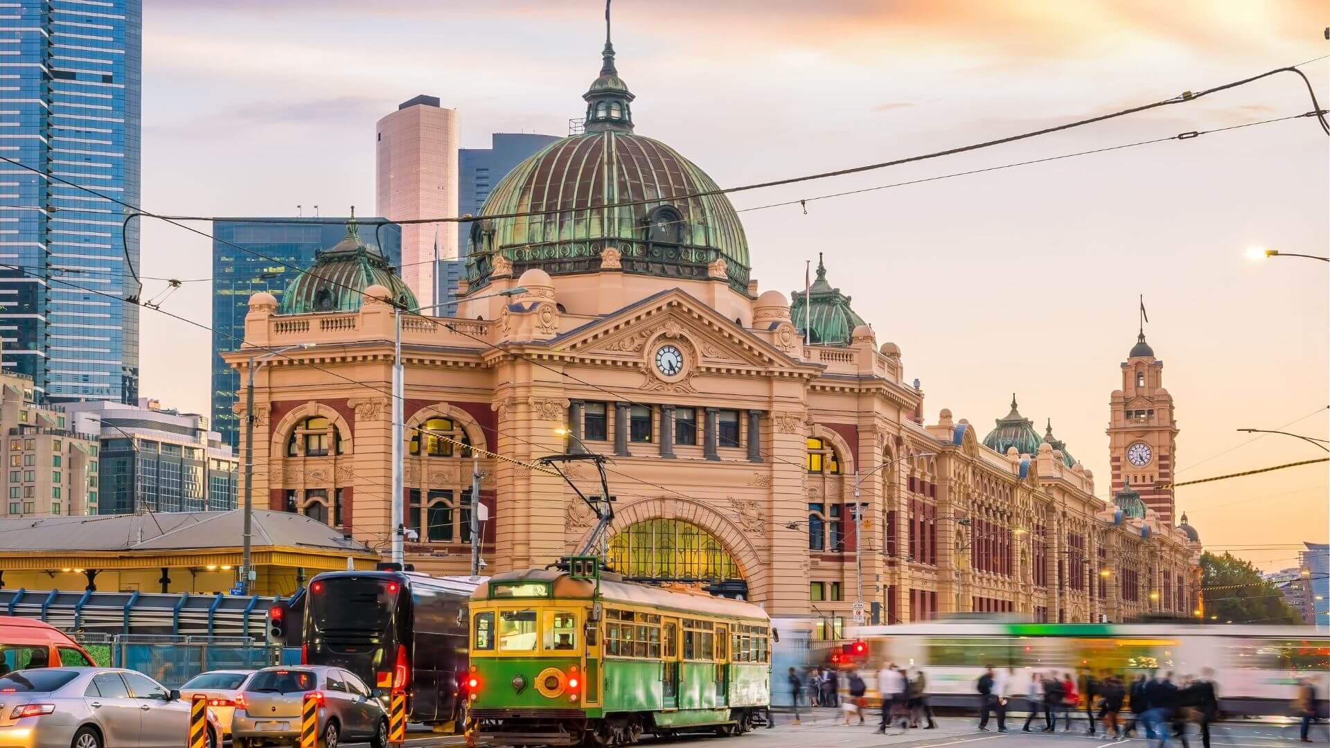 Flinders Street Station, a historic landmark in Melbourne, with trams and buses indicating options for sustainable travel and public transit.