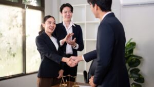 A business professional shaking hands with a client in an office setting, symbolizing trust, agreements, and the steps needed to legally protect your online business.