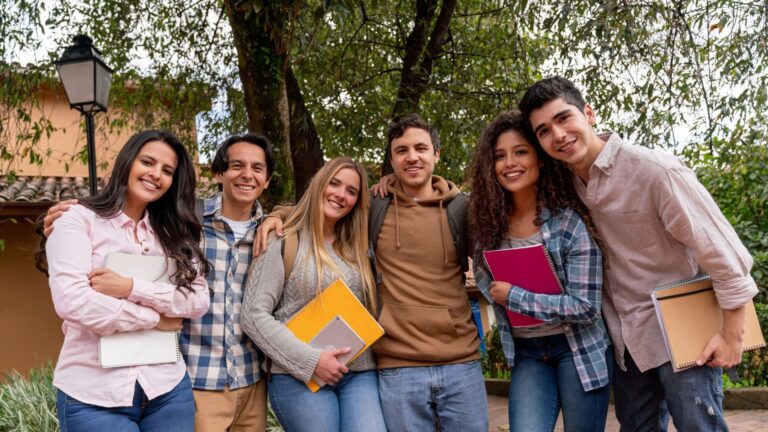 A group of smiling college students standing together on campus, representing the decision-making process for How to Choose the Right College based on community, academics, and environment.