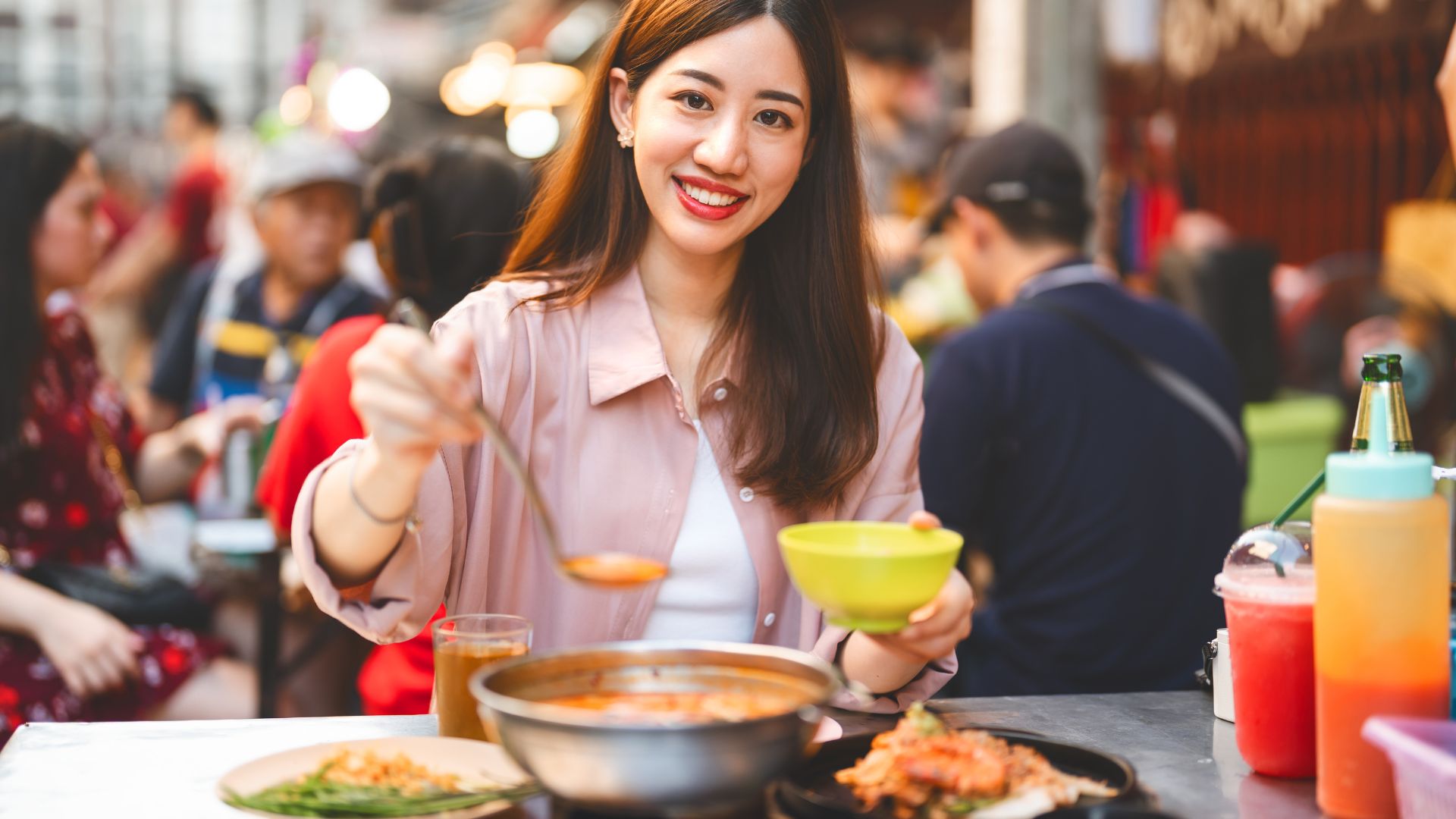 A woman enjoying a bowl of local street food at a vibrant outdoor market, capturing the essence of food driven travel and exploring a destination through its flavors.