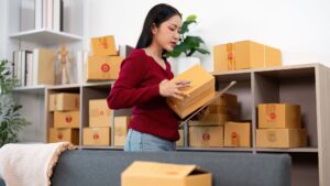 A woman organizing shipping boxes in a small business workspace, representing modern online retail operations and the future of e-commerce.