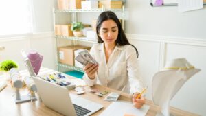 A woman counting cash at her desk while running an online business, representing ways to make money online.