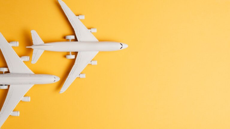 Two white airplane models on a yellow background representing Budget Flight Hacks for 2026: Tricks Airlines Don't Tell You.”