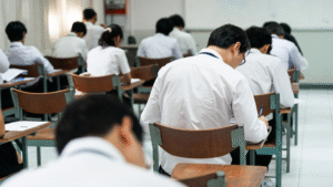 Students sitting in a classroom taking a written test, focused on their work, representing exam tips and strategies for better performance."