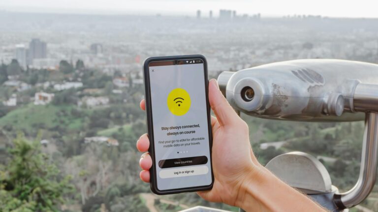 Smartphone showing an eSIM app interface overlooking a city viewpoint, illustrating the best eSIM apps for international travel in 2026 tested across multiple countries.