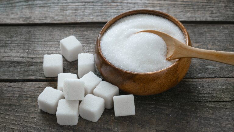 Too much sugar shown with sugar cubes and granulated sugar in a bowl, highlighting how excess sugar intake can cause side effects faster than you think
