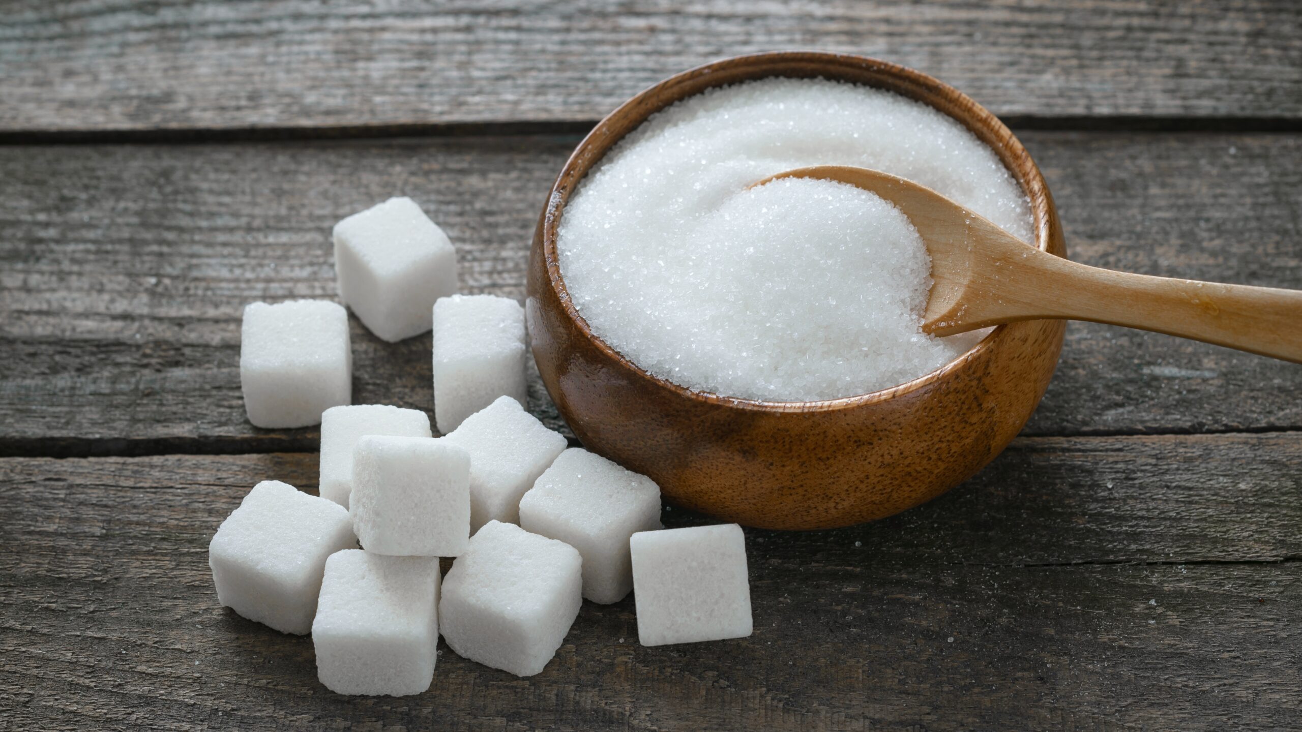Too much sugar shown with sugar cubes and granulated sugar in a bowl, highlighting how excess sugar intake can cause side effects faster than you think
