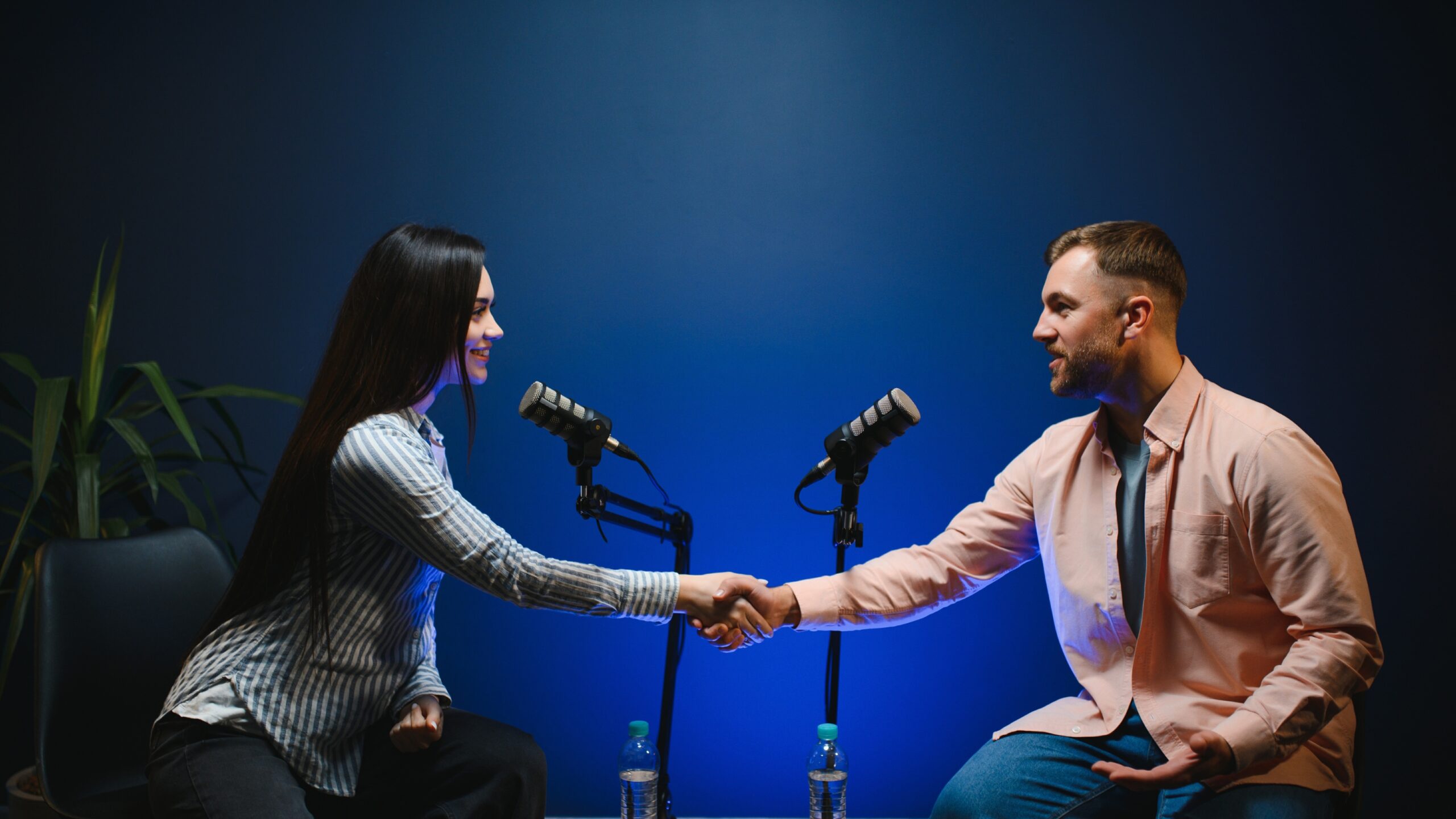 Podcast interview setup with two hosts shaking hands in a professional studio