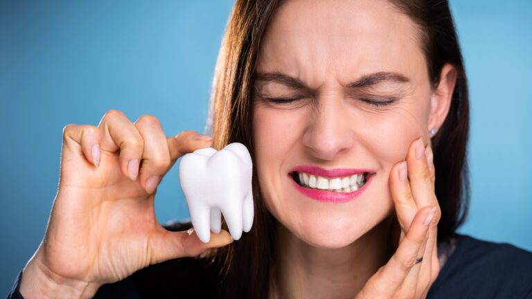 Tooth Pain: Common Reasons and When to See a Dentist – close-up of a woman clenching teeth due to dental pain