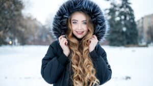 Woman wearing a warm hooded winter jacket outdoors, showcasing winter fashion trends that are actually practical for cold weather
