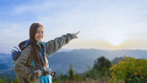 Smiling woman hiking in the mountains at sunrise, ideal for weekend wellness getaways for working professionals