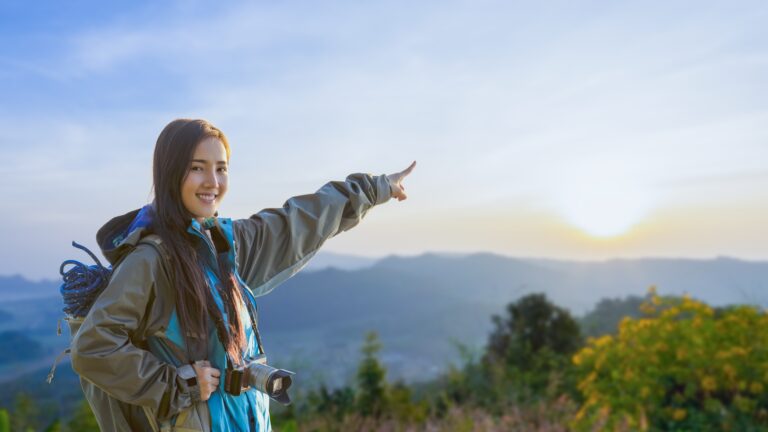 Smiling woman hiking in the mountains at sunrise, ideal for weekend wellness getaways for working professionals
