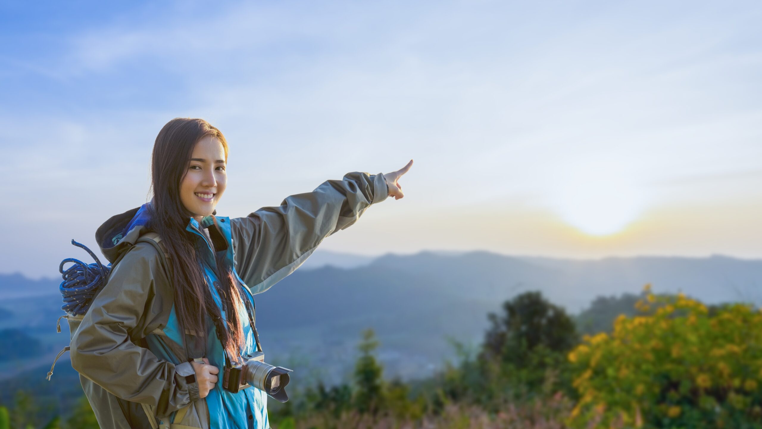 Smiling woman hiking in the mountains at sunrise, ideal for weekend wellness getaways for working professionals