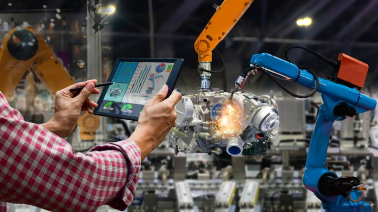 Human operator using a tablet to control robotic arms in a smart factory, showing why businesses still need humans even after AI automation