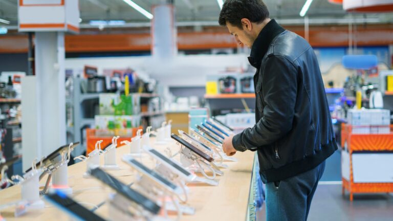 Man comparing the latest smartphones to buy at an electronics store display.