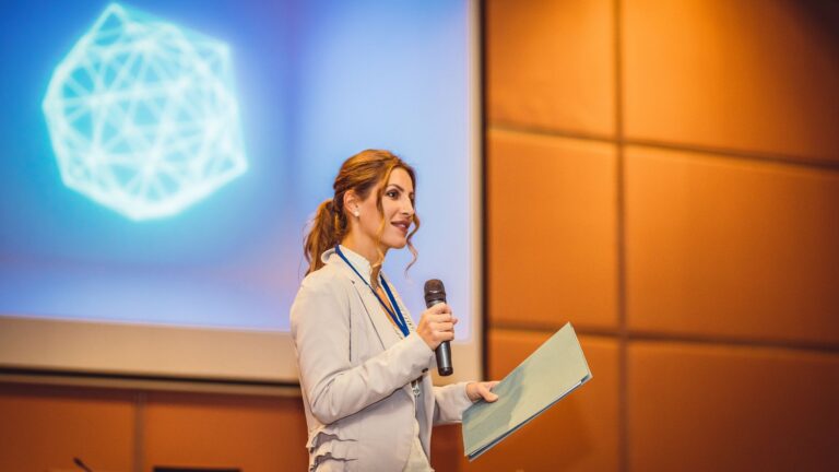 Public Speaking Skills: Online Courses and Practice Techniques illustrated by a professional speaker presenting on stage with a microphone, confidently addressing an audience during a formal presentation.