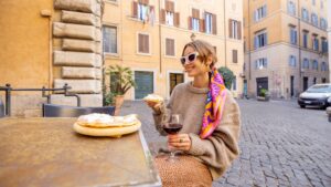 Foodie Adventures: Street Eats to Try in Major Cities, woman enjoying pizza and red wine at a European street café