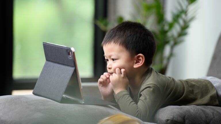 Child watching a tablet at home, illustrating simple habits to reduce daily screen time in modern families