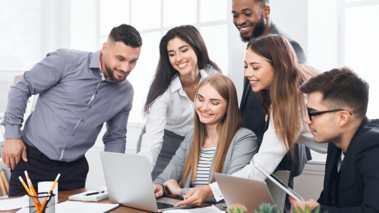 Building Flexible Teams: Hybrid Work Models That Actually Work with employees collaborating around a laptop in a modern office