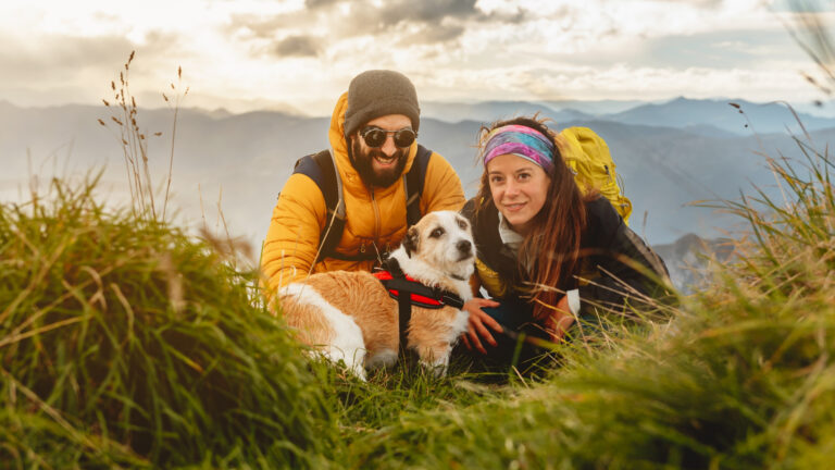 Couple hiking in the mountains with their dog, showcasing pet-friendly destinations in Europe for outdoor travel lovers.